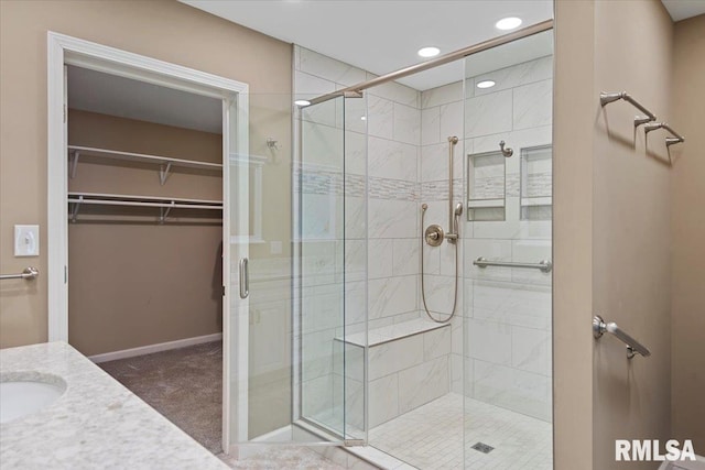 bathroom featuring baseboards, a spacious closet, recessed lighting, vanity, and a stall shower