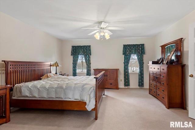 bedroom featuring ceiling fan, multiple windows, light colored carpet, and baseboards