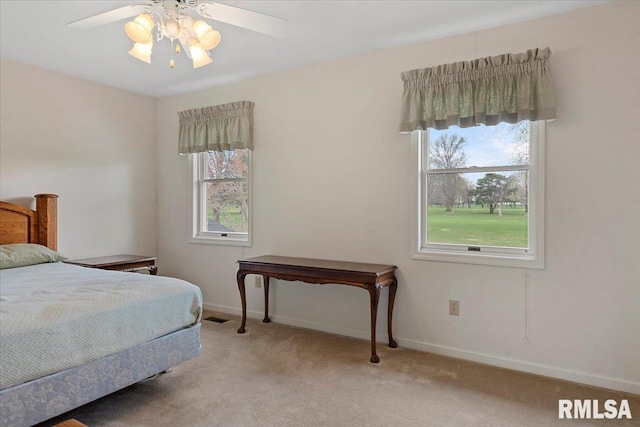 bedroom with a ceiling fan, light carpet, baseboards, and multiple windows