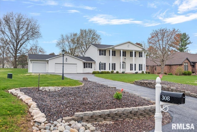 neoclassical / greek revival house with a garage, aphalt driveway, and a front lawn