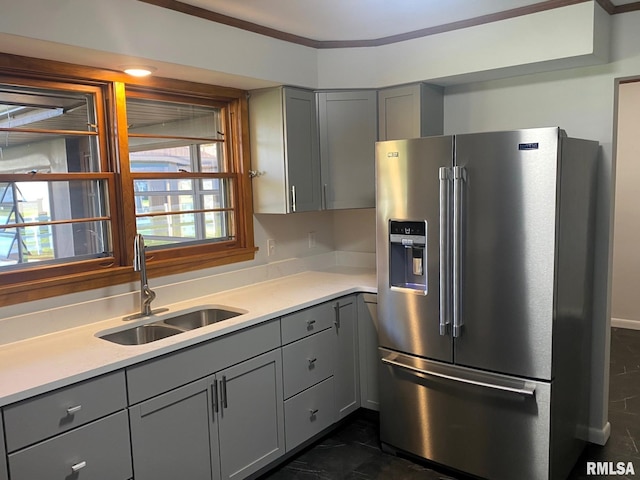kitchen featuring stainless steel refrigerator with ice dispenser, light countertops, a sink, and gray cabinets
