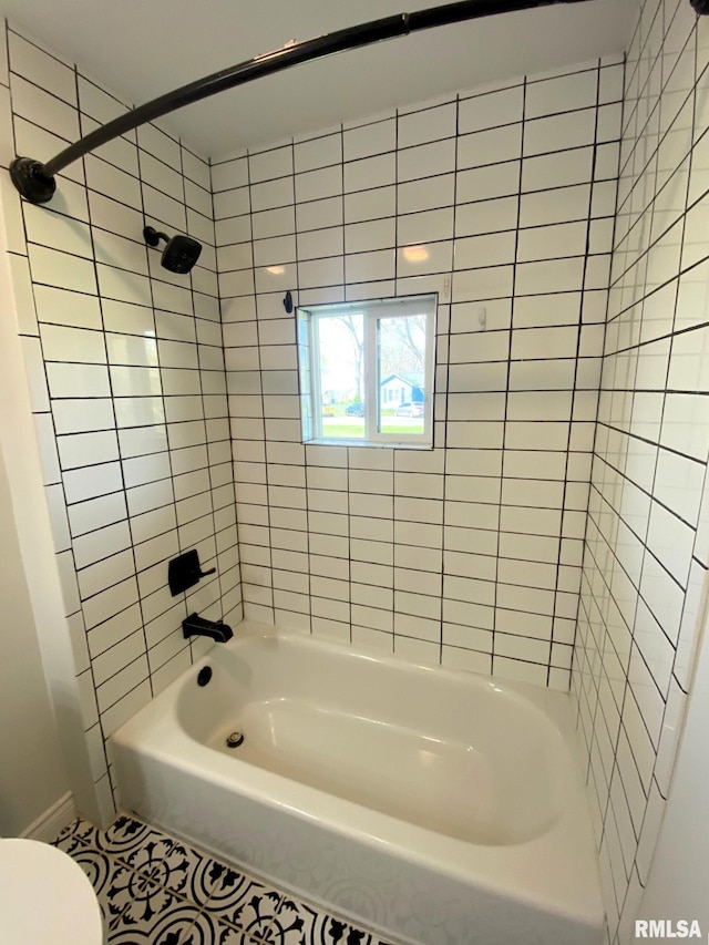 bathroom with toilet, tile patterned floors, baseboards, and shower / bathtub combination