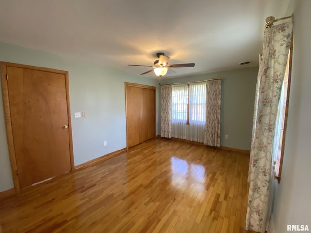 unfurnished bedroom with a closet, light wood finished floors, baseboards, and a ceiling fan