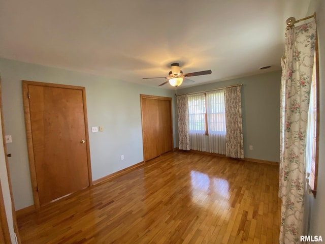 unfurnished bedroom with light wood-style flooring, a closet, baseboards, and a ceiling fan