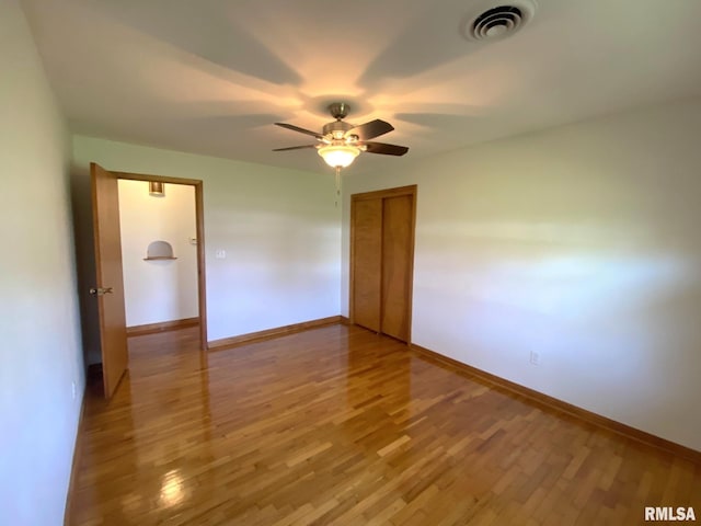 empty room featuring light wood finished floors, visible vents, baseboards, and ceiling fan