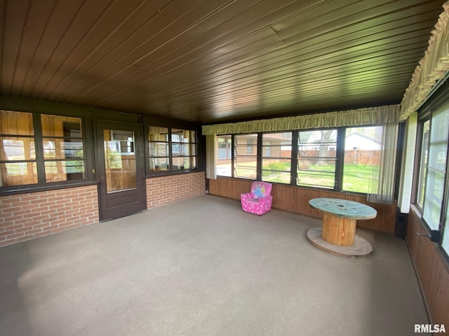 unfurnished sunroom featuring brick wall and wooden ceiling