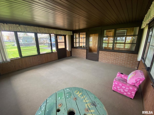 sunroom / solarium featuring carpet floors and brick wall