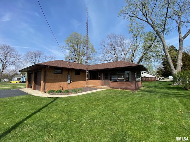 rear view of house with roof with shingles, aphalt driveway, brick siding, a porch, and a lawn