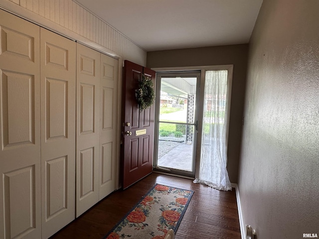 foyer entrance featuring a textured wall and dark wood finished floors