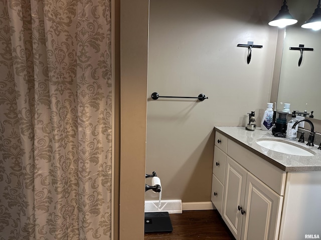 bathroom with vanity, visible vents, baseboards, and wood finished floors
