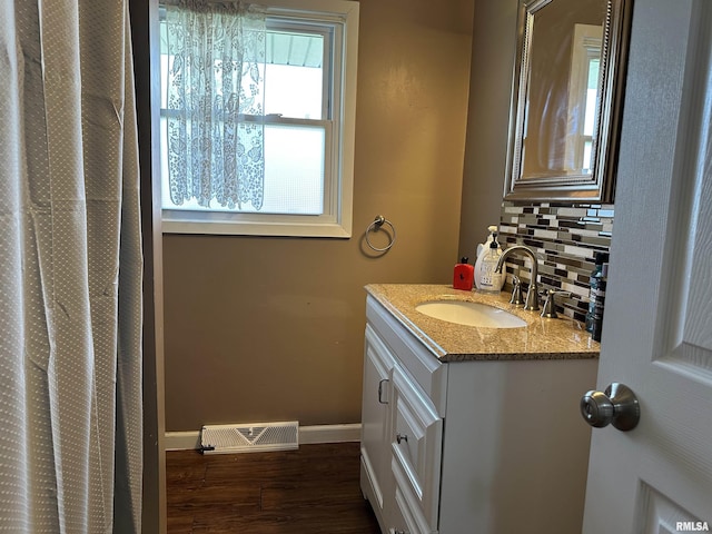 full bathroom featuring tasteful backsplash, vanity, visible vents, wood finished floors, and baseboards