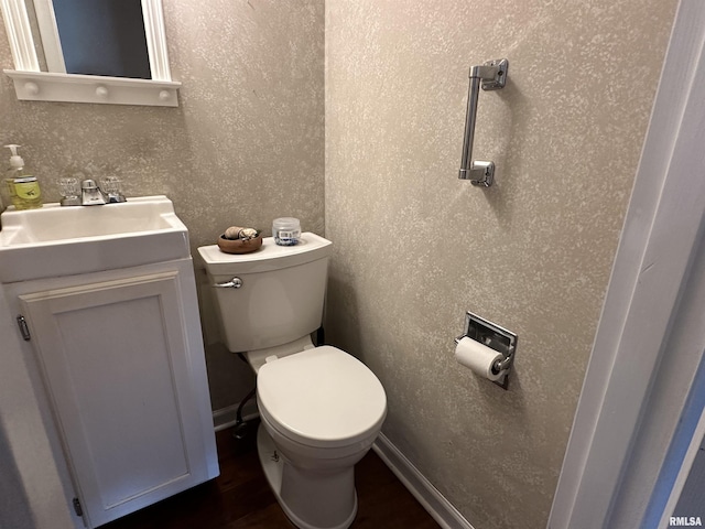 half bath featuring toilet, wood finished floors, and vanity