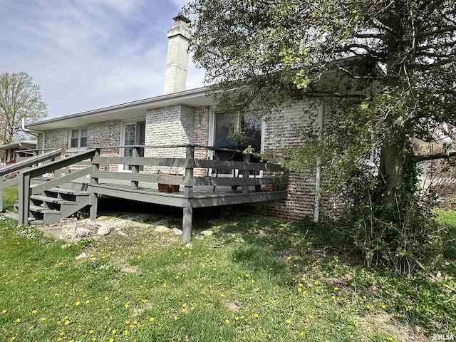 exterior space with brick siding, a deck, and a chimney