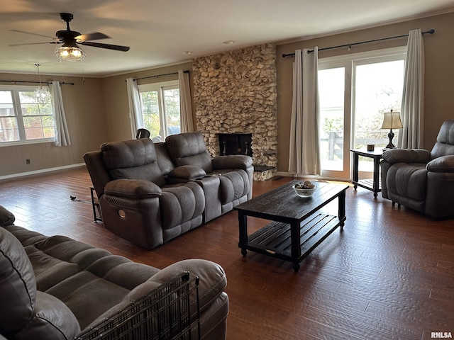 living area with a fireplace, ceiling fan, wood finished floors, and a healthy amount of sunlight