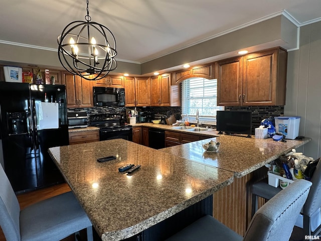 kitchen with an inviting chandelier, black appliances, a breakfast bar area, brown cabinetry, and a sink