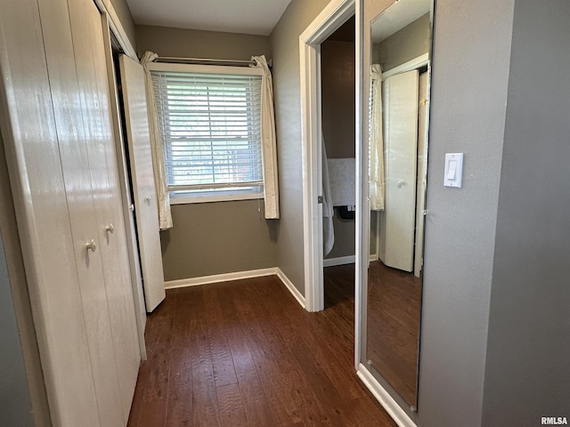 corridor featuring dark wood-type flooring and baseboards