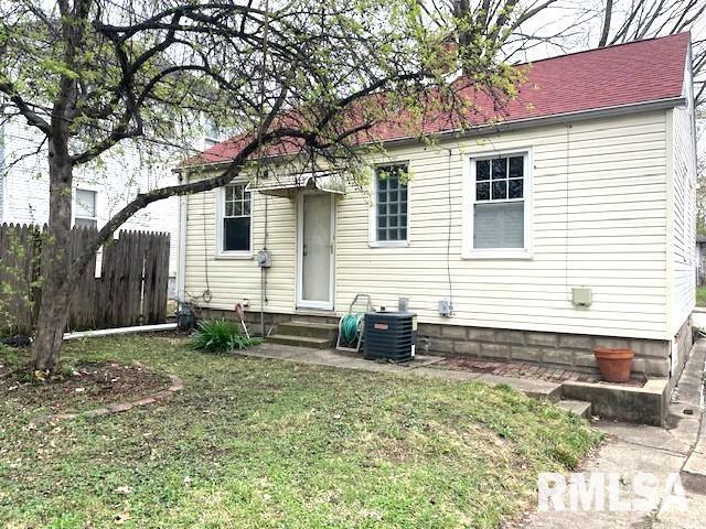 rear view of house with a yard, central air condition unit, entry steps, and fence