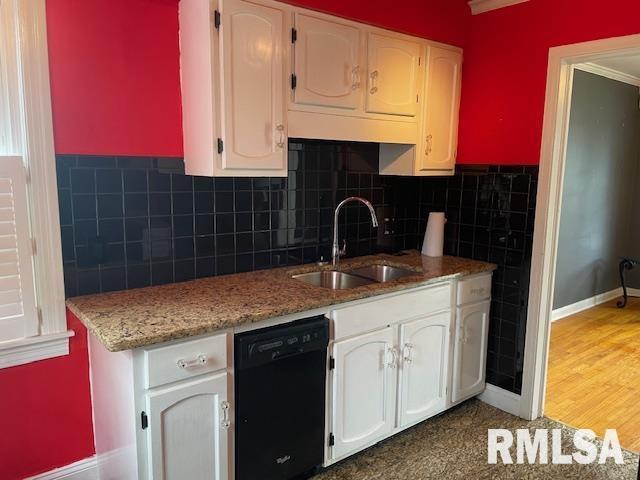 kitchen featuring white cabinets, black dishwasher, light stone counters, a sink, and baseboards