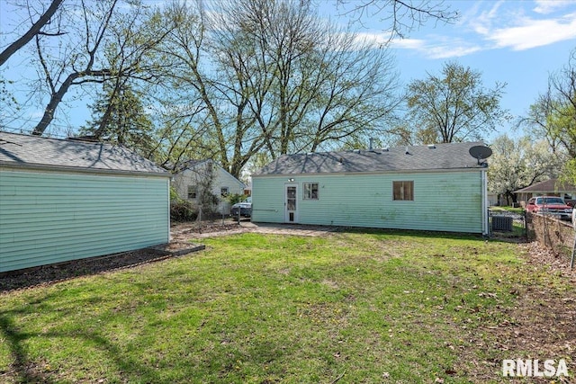 rear view of house with fence and a lawn
