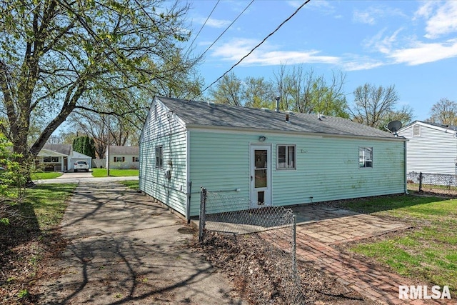 rear view of property featuring driveway, a patio area, and fence