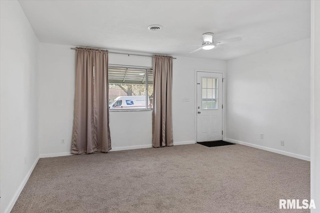 carpeted spare room featuring baseboards, a ceiling fan, and visible vents