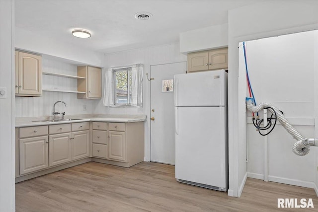 kitchen with light countertops, light wood-style floors, a sink, and freestanding refrigerator