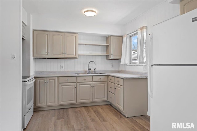 kitchen with white appliances, light wood-style floors, light countertops, and a sink
