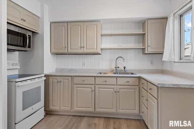 kitchen featuring stainless steel microwave, light countertops, electric range, light wood-style floors, and a sink