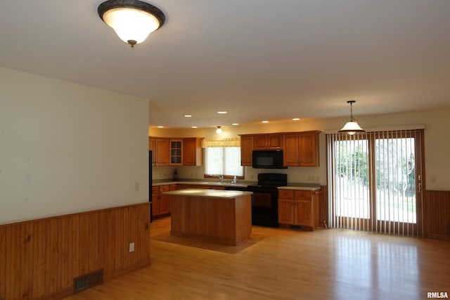 50 Hackberry Cir, Galesburg, IL 61401 - kitchen featuring black appliances, brown cabinets, wainscoting, a center island, and glass insert cabinets