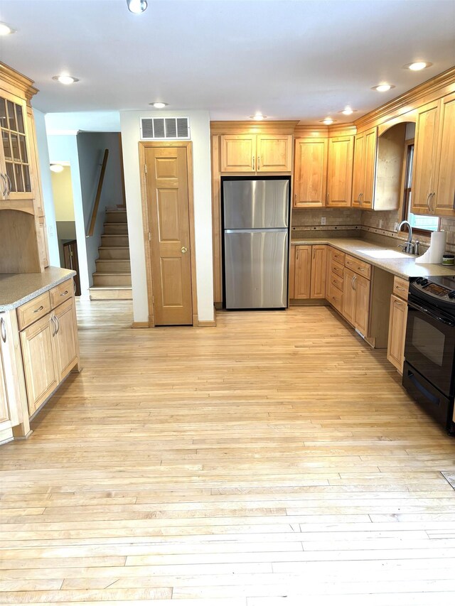 2110 Magnolia Dr, Jacksonville, IL 62650 - kitchen featuring light wood-type flooring, freestanding refrigerator, black electric range oven, visible vents, and a sink