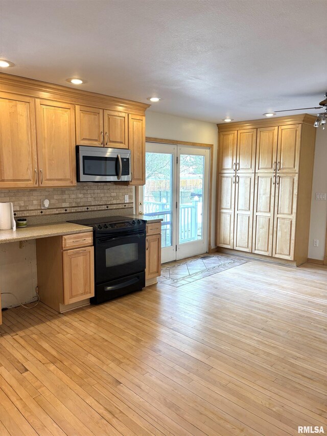 2110 Magnolia Dr, Jacksonville, IL 62650 - kitchen featuring stainless steel microwave, recessed lighting, backsplash, black electric range oven, and light wood-style floors