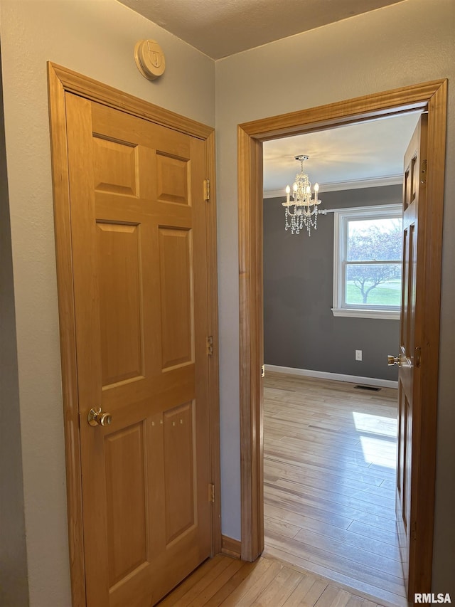 2110 Magnolia Dr, Jacksonville, IL 62650 - hallway featuring light wood-style floors, baseboards, an inviting chandelier, and visible vents