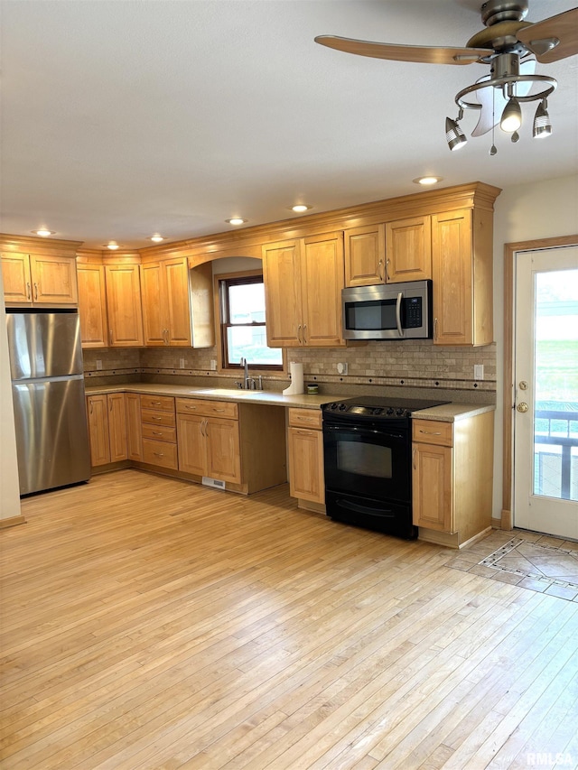 2110 Magnolia Dr, Jacksonville, IL 62650 - kitchen featuring appliances with stainless steel finishes, a sink, a healthy amount of sunlight, decorative backsplash, and ceiling fan