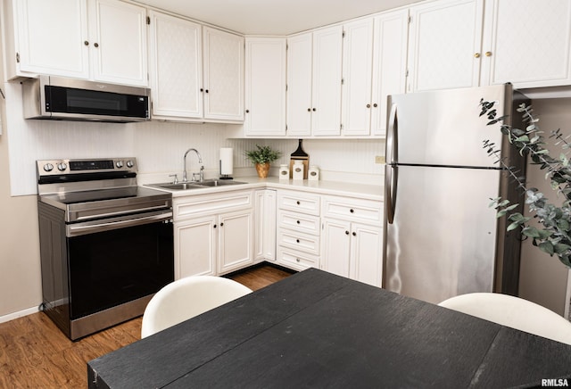 kitchen with dark wood-type flooring, white cabinetry, a sink, and appliances with stainless steel finishes