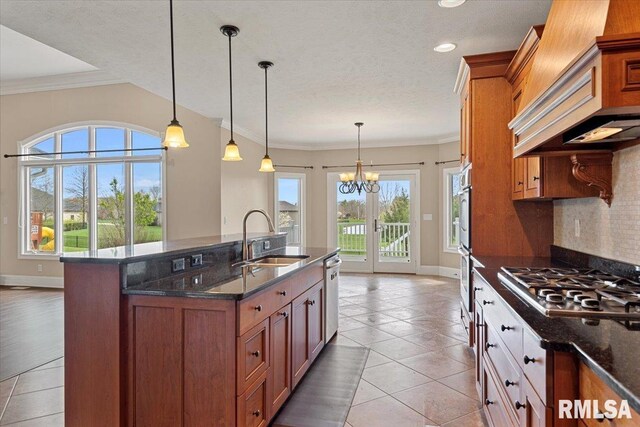 kitchen featuring an inviting chandelier, custom exhaust hood, a sink, stainless steel appliances, and brown cabinets