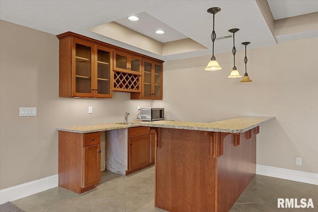 bar with hanging light fixtures, baseboards, a raised ceiling, stainless steel microwave, and light tile patterned flooring