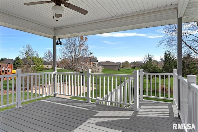 wooden deck with ceiling fan, a residential view, and a lawn