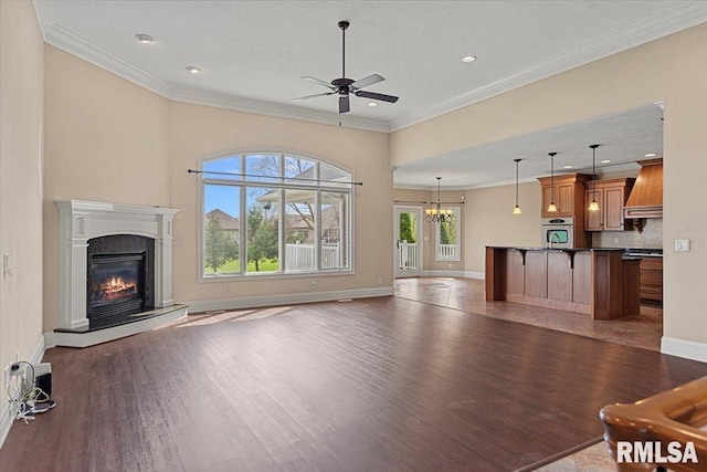 unfurnished living room with ceiling fan with notable chandelier, a fireplace, recessed lighting, wood finished floors, and baseboards