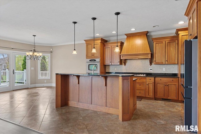 kitchen featuring brown cabinets, dark countertops, premium range hood, and stainless steel appliances