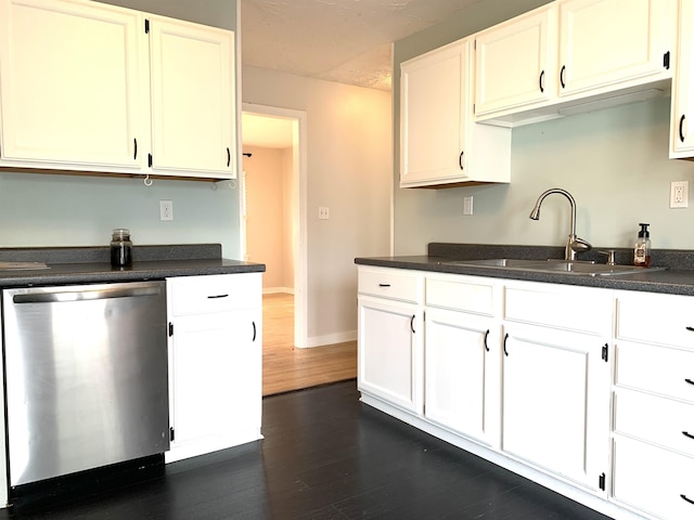kitchen featuring white cabinets, dark wood finished floors, dark countertops, dishwasher, and a sink