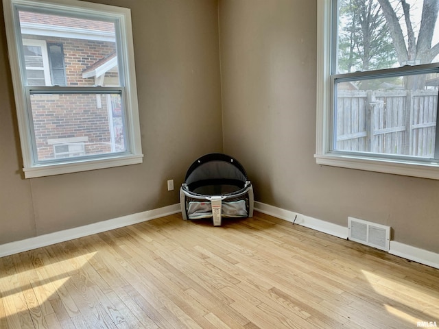 unfurnished room featuring wood finished floors, visible vents, and baseboards