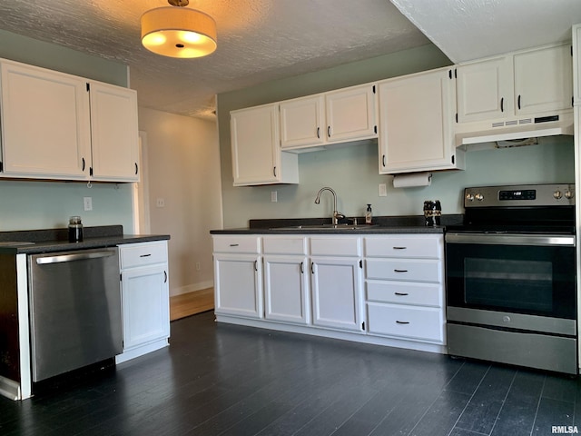kitchen with white cabinets, stainless steel appliances, a sink, dark countertops, and under cabinet range hood