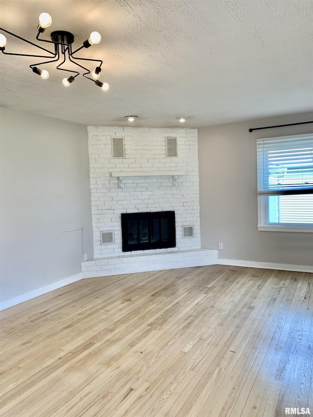 unfurnished living room featuring visible vents, a textured ceiling, a notable chandelier, and wood-type flooring