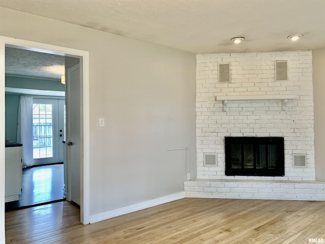 unfurnished living room with visible vents, baseboards, wood finished floors, and a fireplace