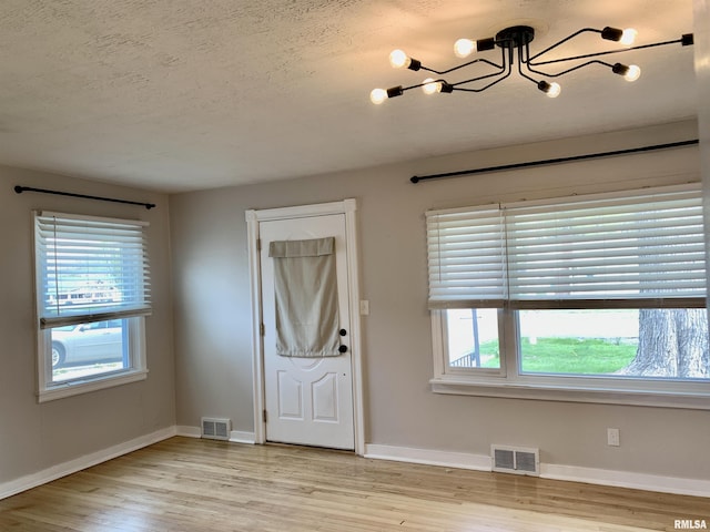 entryway featuring plenty of natural light, visible vents, and a chandelier