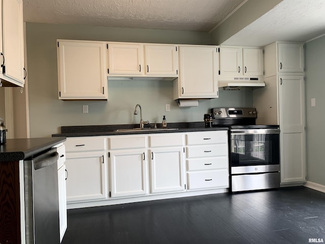 kitchen featuring white cabinets, under cabinet range hood, stainless steel appliances, dark countertops, and a sink