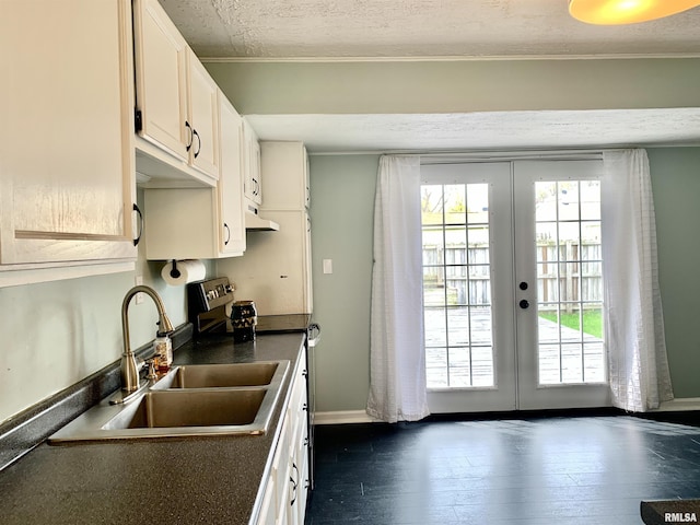 kitchen featuring dark countertops, a sink, a textured ceiling, french doors, and under cabinet range hood