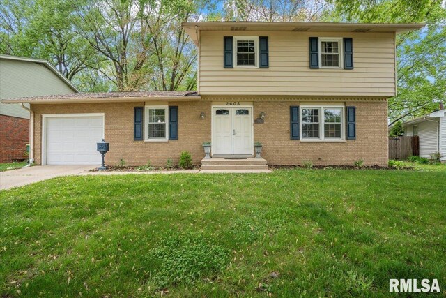 view of front of house with a garage, concrete driveway, a front lawn, and brick siding