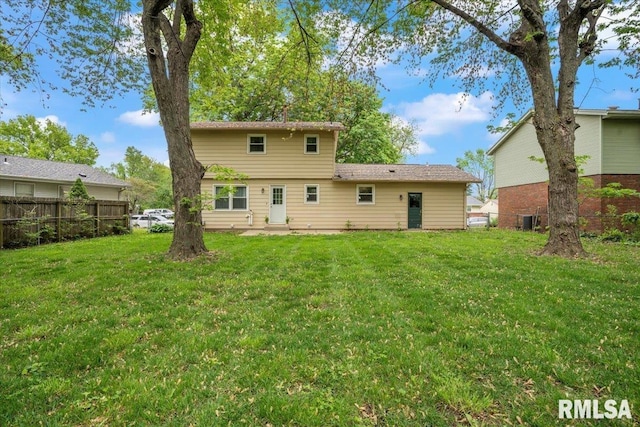 rear view of house with fence, a yard, and cooling unit