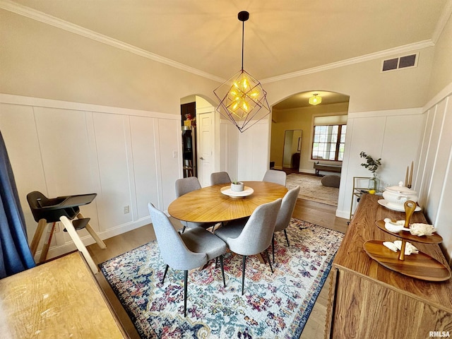 3096 Whitehaven Cir, Galesburg, IL 61401 - dining room featuring a decorative wall, crown molding, arched walkways, light wood finished floors, and visible vents
